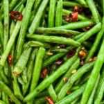 Bright green long beans are fried with sliced chilis.